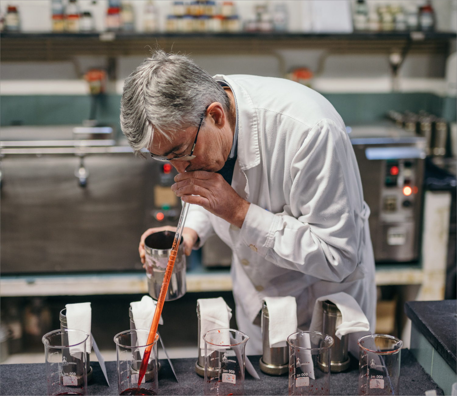 An elderly man using a pipette in a laboratory setting.