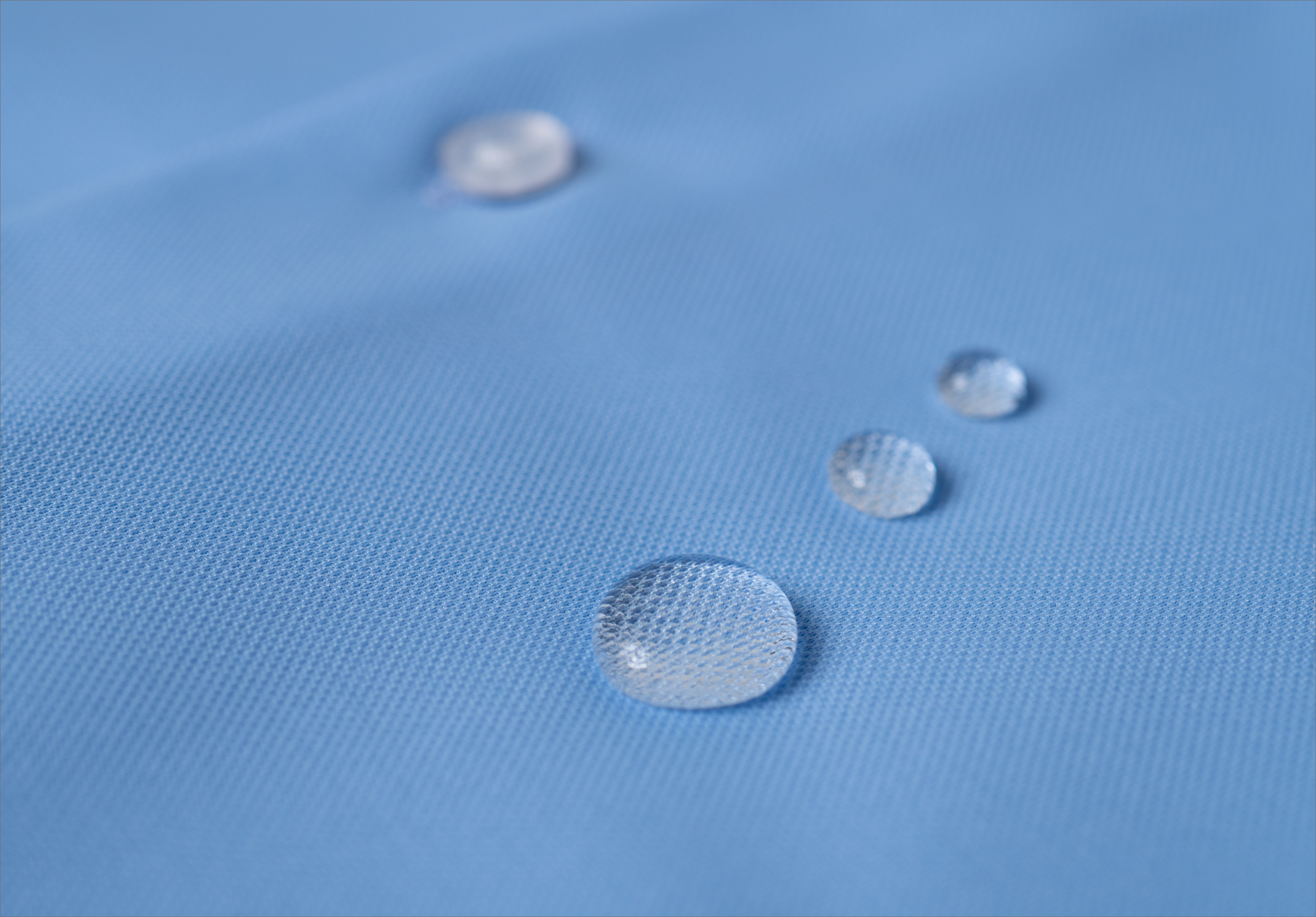 Zoomed-in picture of water droplets on a piece of blue fabric.
